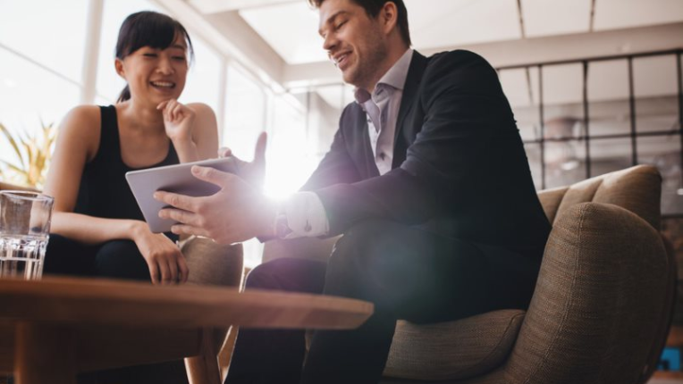 Two business people sitting on a couch looking at a tablet